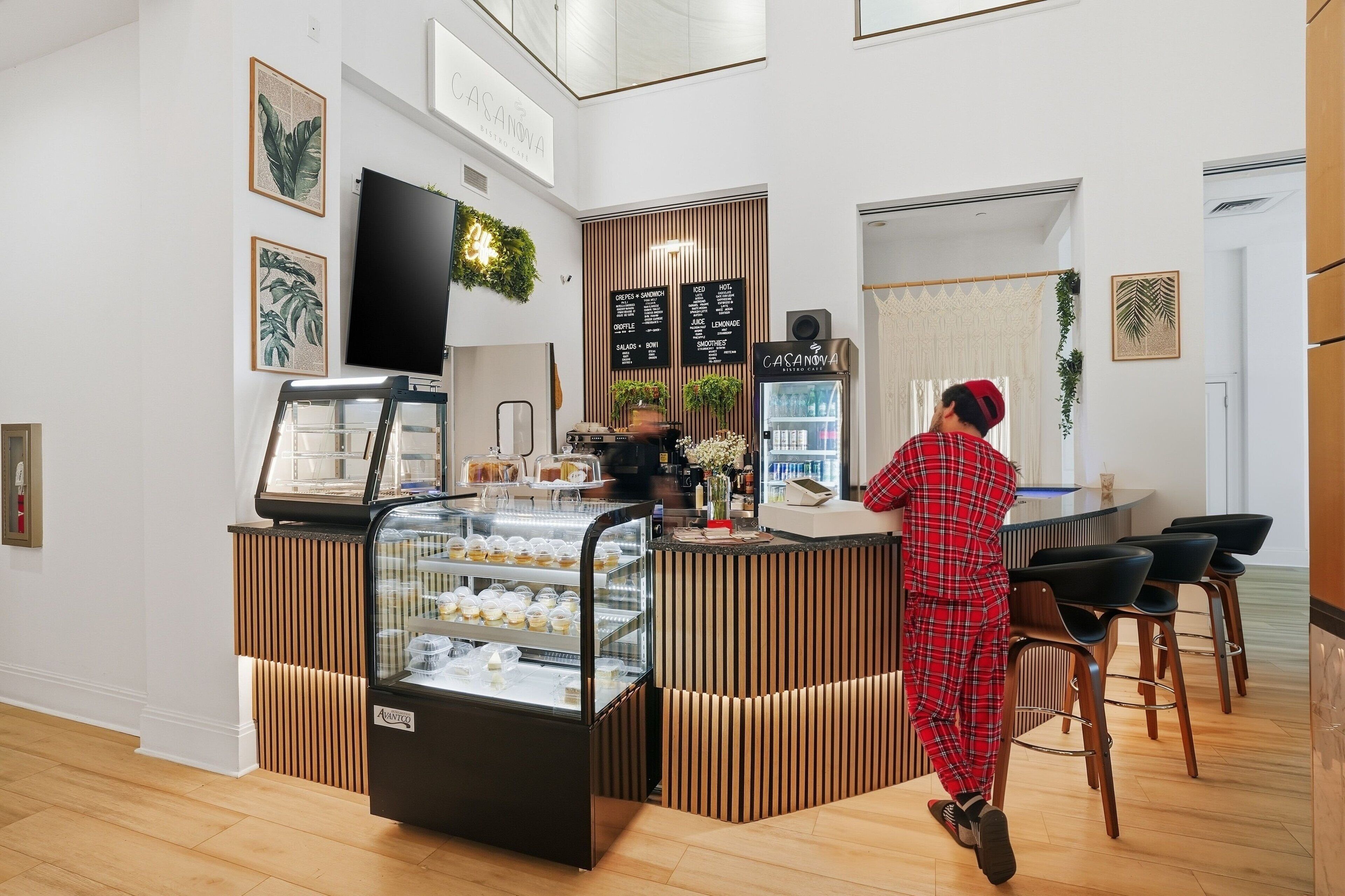 Un café moderne avec un comptoir, un espace salon et des panneaux d’affichage présentant le menu.