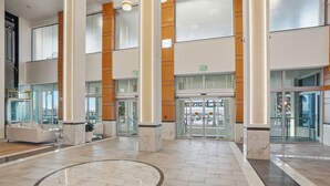 A spacious lobby with marble flooring, large columns, and glass doors leading to an outdoor area. - Luxurious Waterfront Condo At Alta Mar 2 Bedroom Condo (Fort Myers)