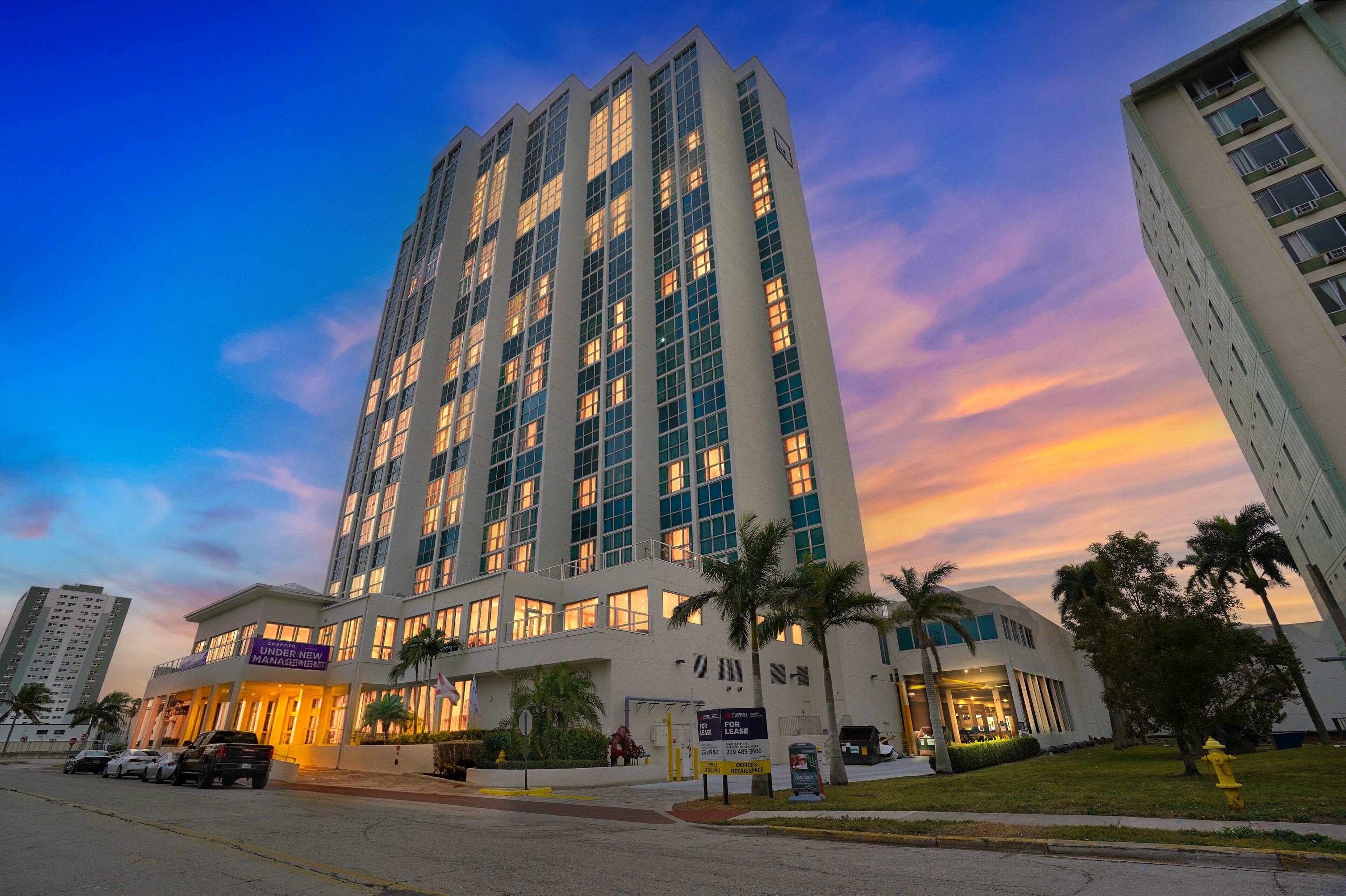 A high-rise hotel with multiple floors, a prominent entrance, and a parking area in front.