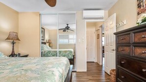 Een slaapkamer met een bed, een plafondventilator, een dressoir en een deur naar een andere kamer.
