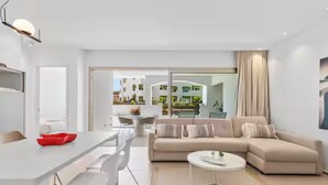 A modern living room with a sofa, a dining table, and a kitchen visible through an open door. - BEAUTIFUL APARTMENT IN RESIDENCE JARDINES DE LOS MENCEYES HEATED SWIMMING POOL (Palm-Mar)