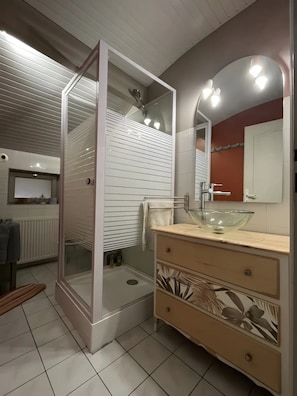 A modern bathroom with a glass shower enclosure, a sink with a glass bowl, and a vanity with drawers. - Léontine Guest Room – Canal des Deux Mers by Bike (Lamagistère)