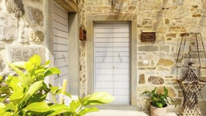 Un bâtiment en pierre avec une porte fermée par un volet, une enseigne indiquant « Ramerino », et un pot de fleurs en premier plan.