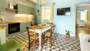 Un coin repas avec une table et des chaises en bois, un lustre et un téléviseur fixé au mur.
