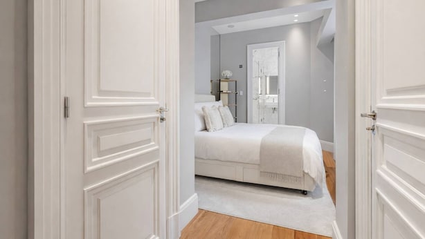 Une chambre à coucher comprenant un lit, une table de chevet, une commode et un miroir.