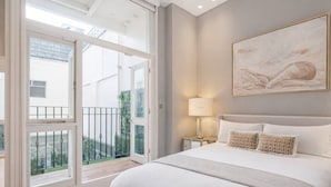Une chambre à coucher avec un grand lit, une table de chevet, une lampe et un tableau au mur.
