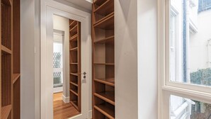 Un dressing accessible sans porte, doté de plusieurs étagères en bois et d’une porte donnant sur une autre pièce.