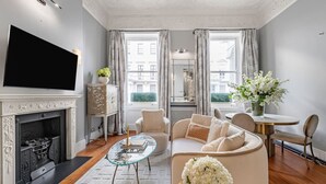 Un salon moderne doté d’une cheminée, d’un téléviseur à écran plat, d’un canapé et d’un coin repas avec une table et des chaises.