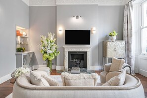 Ein Wohnzimmer mit Kamin, Fernseher und einer Couch.