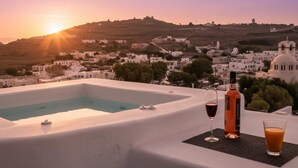 A rooftop pool with a sunset view of a white-washed town, a bottle of wine, and a glass of wine on a mat. - Poseidon’s Water Escape Santorini Rooftop Jacuzzi (Santorini)