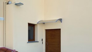 Un bâtiment doté d’une cour pavée de pierres, d’une porte en bois et d’une petite fenêtre.