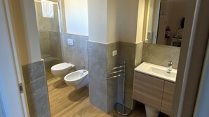 Une salle de bain moderne équipée d’une douche, de toilettes, d’un bidet et d’un lavabo.