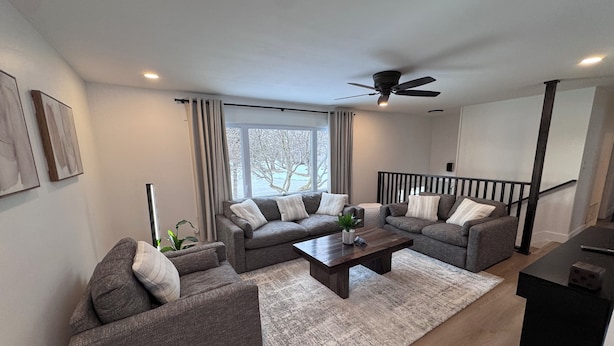 A modern living room with two grey sofas, a wooden coffee table, and a large window with curtains.