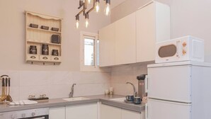 Una cocina moderna con armarios blancos, horno empotrado, cafetera y microondas.