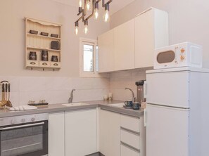 Eine moderne Küche mit weißen Schränken, einem eingebauten Ofen, einer Kaffeemaschine und einer Mikrowelle.