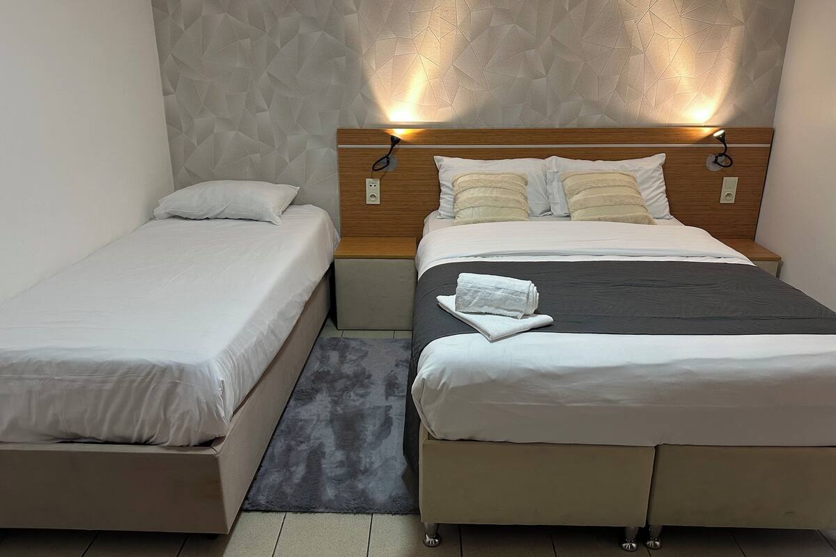 Une chambre double avec deux lits, une tête de lit en bois et un mur à texture.