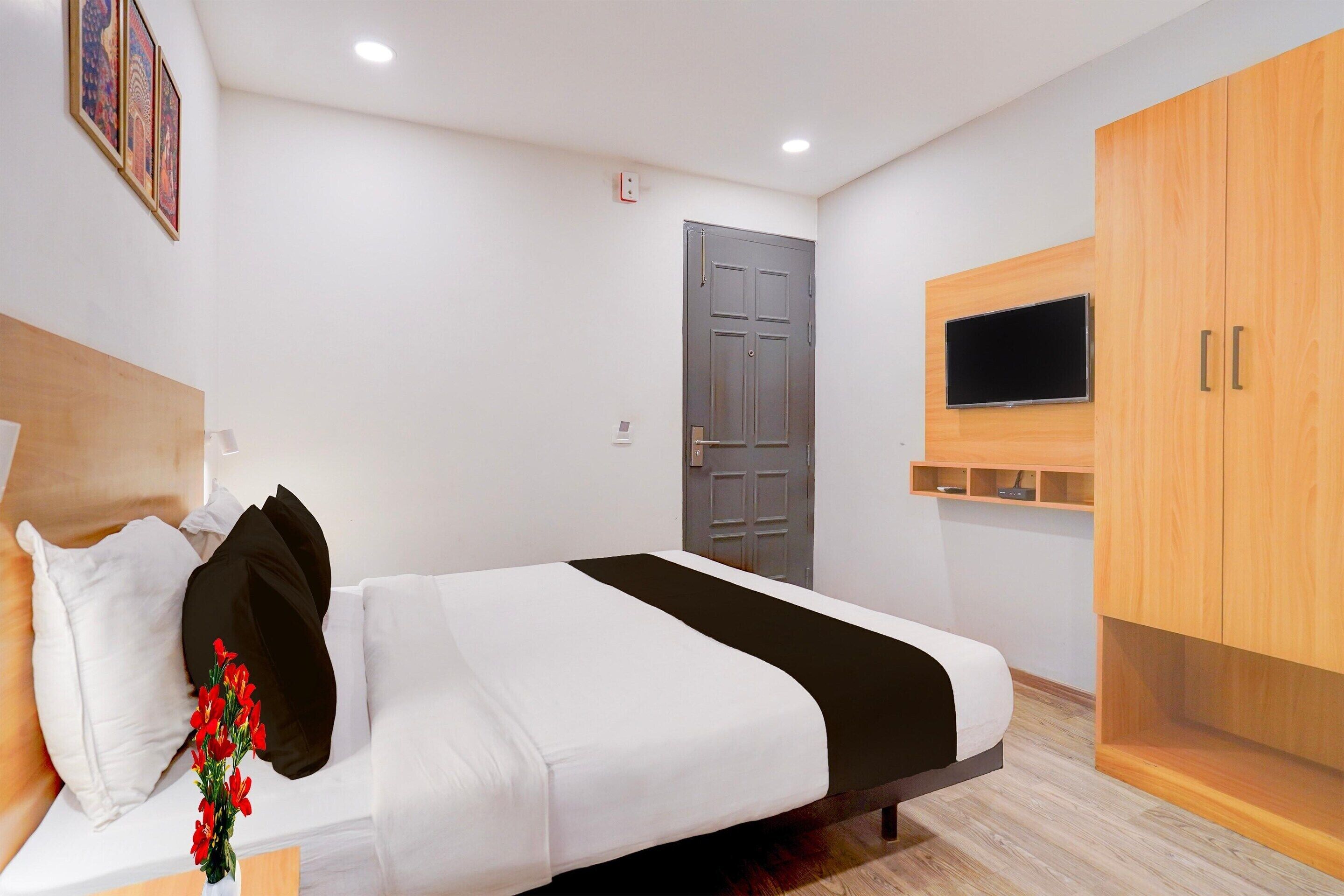 Quarto de hotel moderno com cama, televisão presa na parede e guarda-roupa.