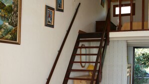 Une pièce avec un escalier en bois, un lit avec un oreiller et un tableau accroché au mur.