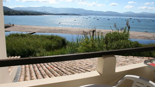 Un balcon avec vue sur une plage et des bateaux sur l’eau.