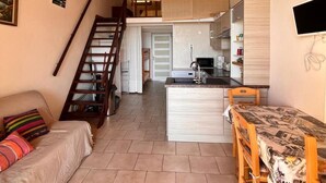 Un espace de vie compact comprenant une cuisine, un coin repas et un escalier menant à un niveau supérieur.
