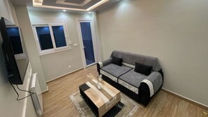 A modern living room with a grey sofa, a wooden coffee table, and a flat-screen TV.