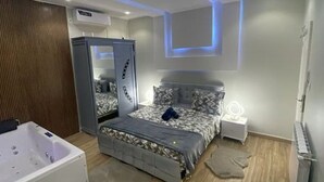 A modern bedroom with a bed, a vanity, and a large mirror cabinet.