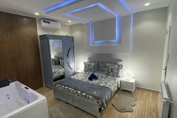 A modern bedroom with a bed, a vanity, and a large mirror cabinet.
