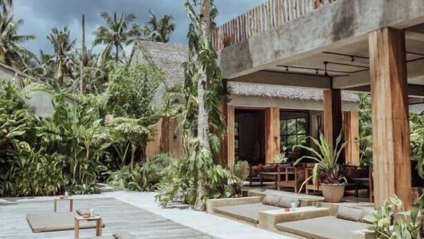 A wooden deck with lounge chairs, surrounded by tropical plants and a wooden structure with seating. - Surfing Temple Boutique Hotel (General Luna)
