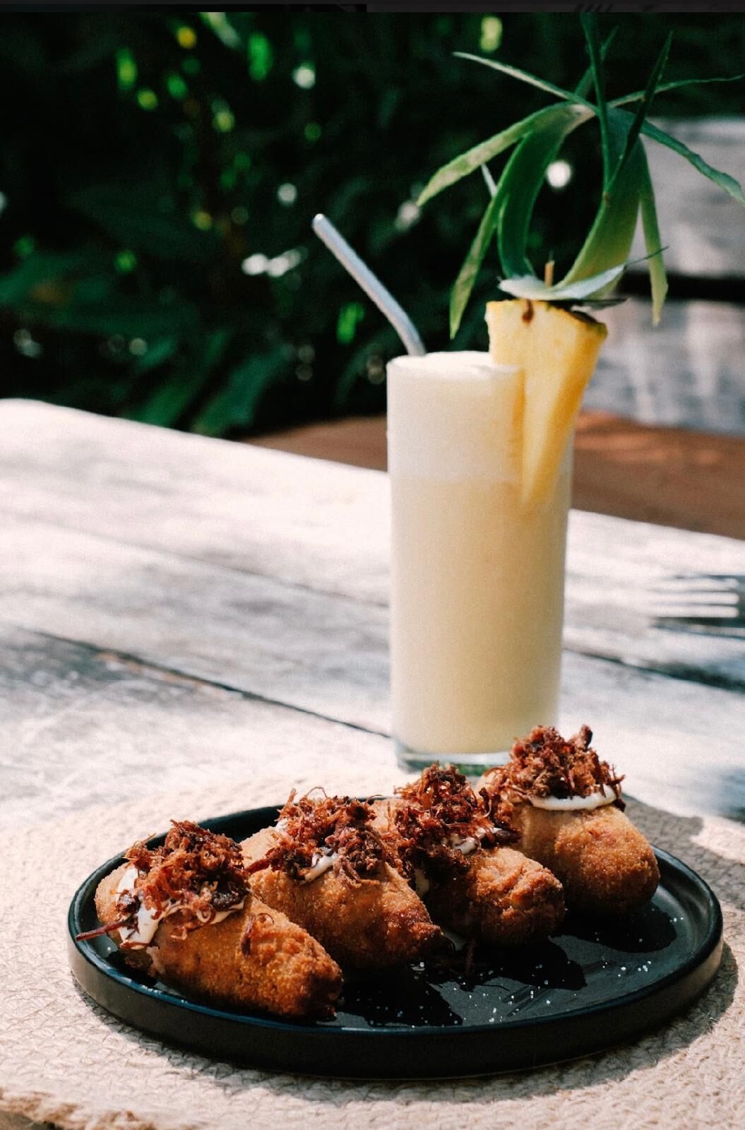 A plate of fried food with a drink in the background.