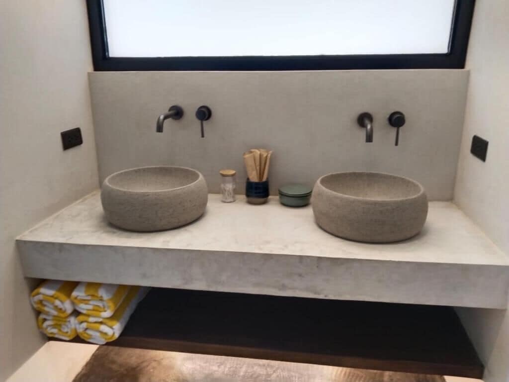 Une salle de bain avec deux lavabos ronds, un porte-serviettes et une étagère.