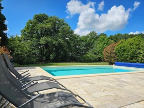 A swimming pool with lounge chairs, surrounded by trees and a clear sky. - Private Estate with Pool – Apartment + Poolhouse near Versailles & Paris (Neauphle-le-Château)