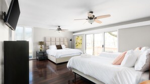 A modern hotel room with two beds, a flat-screen TV, ceiling fans, and large windows. - The Mid-Century Modern House - Long Term Available (Seguin)
