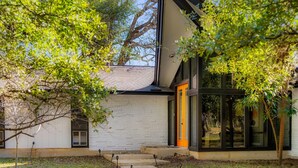 A modern house with a white exterior, a black roof, and a glass door. - The Mid-Century Modern House - Long Term Available (Seguin)