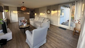 A living room with a sofa, armchairs, a coffee table, and a TV.