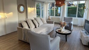 A modern living room with a sofa, striped armchairs, a coffee table, and a TV.