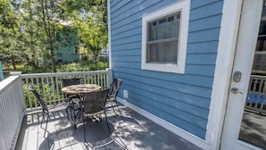 A blue house with a white door and window, a porch with a table and chairs, and a white railing. - Beachwalk Resort Guest House w/Pool, Beach, More (Michigan City)