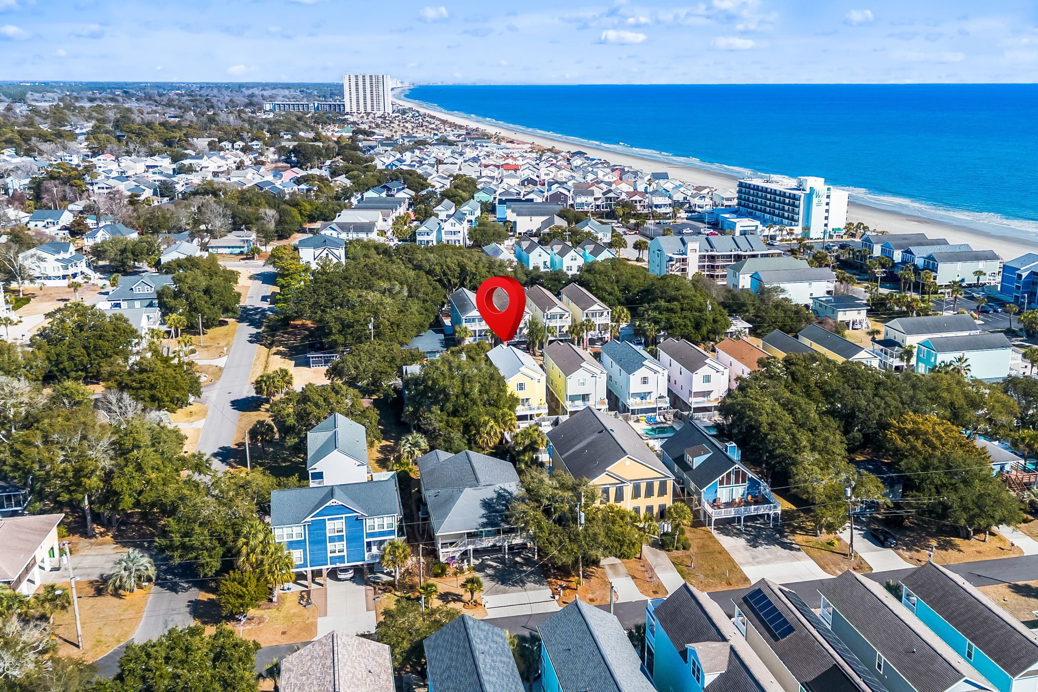 Vista aérea de uma área residencial costeira com casas, uma praia e um hotel.