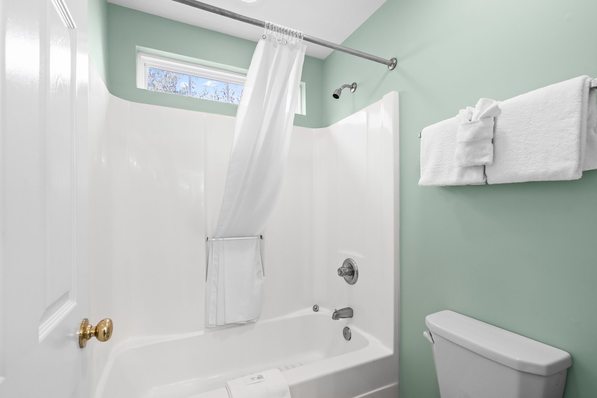 Ein Badezimmer mit Badewanne, Duschvorhang, Handtuchhalter und Toilette.