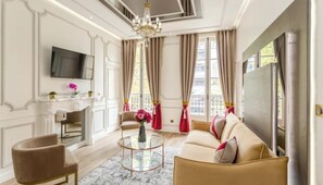 Un salón espacioso con un sofá beige, una mesa de centro redonda y un televisor montado en la pared.