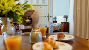 A breakfast table with plates of food, a glass of orange juice, and a vase of flowers. - Agriturismo gli Archi (Fauglia)