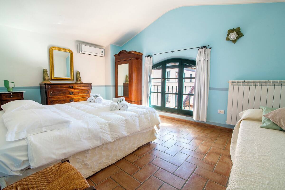 Une chambre à coucher avec un lit, une commode et une fenêtre donnant sur un beau paysage.