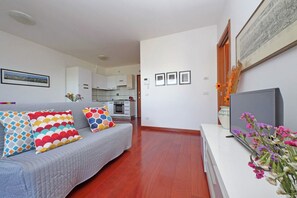 A living room with a grey sofa, colorful cushions, a flat-screen TV, and a vase with flowers. - Modern flat with terrace near Eataly (Roma)