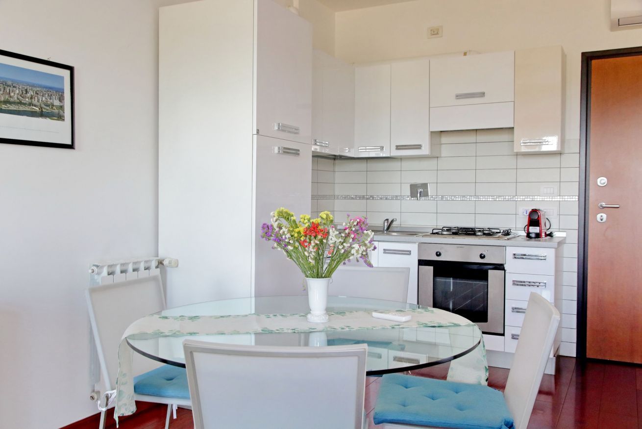 A compact kitchen with white cabinets, a stove, and a coffee maker.