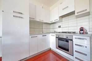 A modern kitchen with white cabinets, a stainless steel oven, and a tiled backsplash. - Modern flat with terrace near Eataly (Roma)
