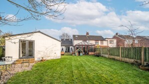 A residential property with a well-maintained lawn, a small playhouse, and a patio area with outdoor furniture. - Wood burner, two lounges and a large garden for up to 8 guests (South Hiendley)