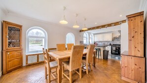 A spacious kitchen with wooden flooring, a dining table with chairs, and a large window providing natural light. - Wood burner, two lounges and a large garden for up to 8 guests (South Hiendley)