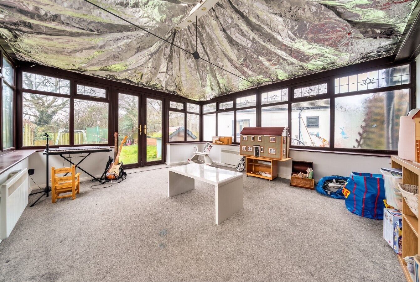 A room with a large window, a white desk, and a bookshelf.
