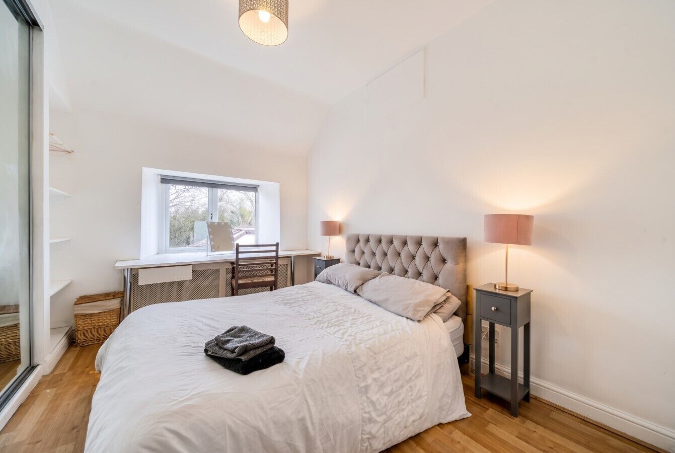 A bedroom with a large bed, a desk, and a window.