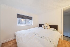 A bedroom with a bed, a window with a view, and a door leading to another room.