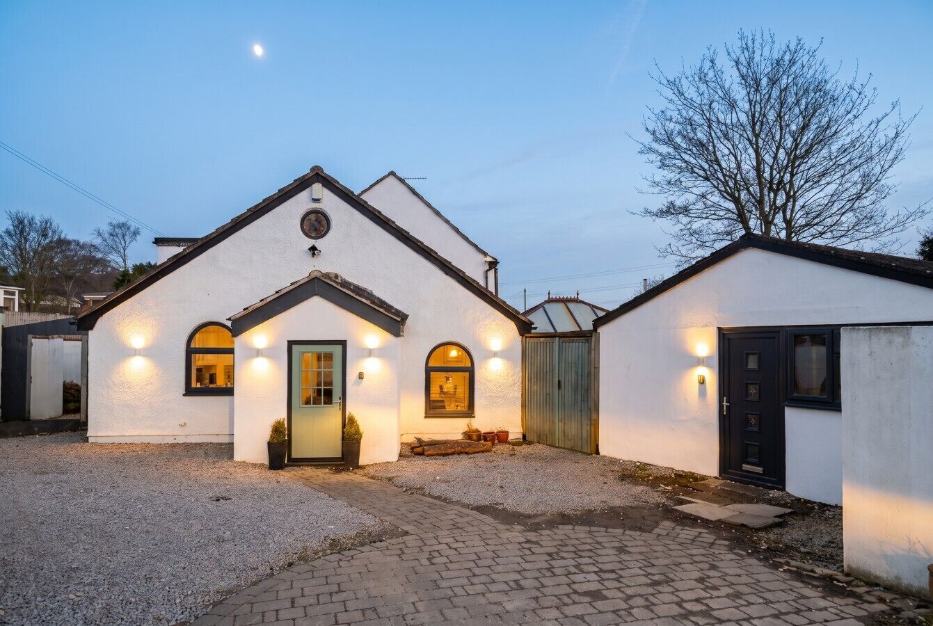 A building with a white facade, a central entrance, and a gravel driveway.